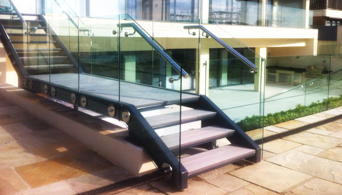 Contemporary mild steel exterior staircase with stainless steel handrails and structural glass balustrade.